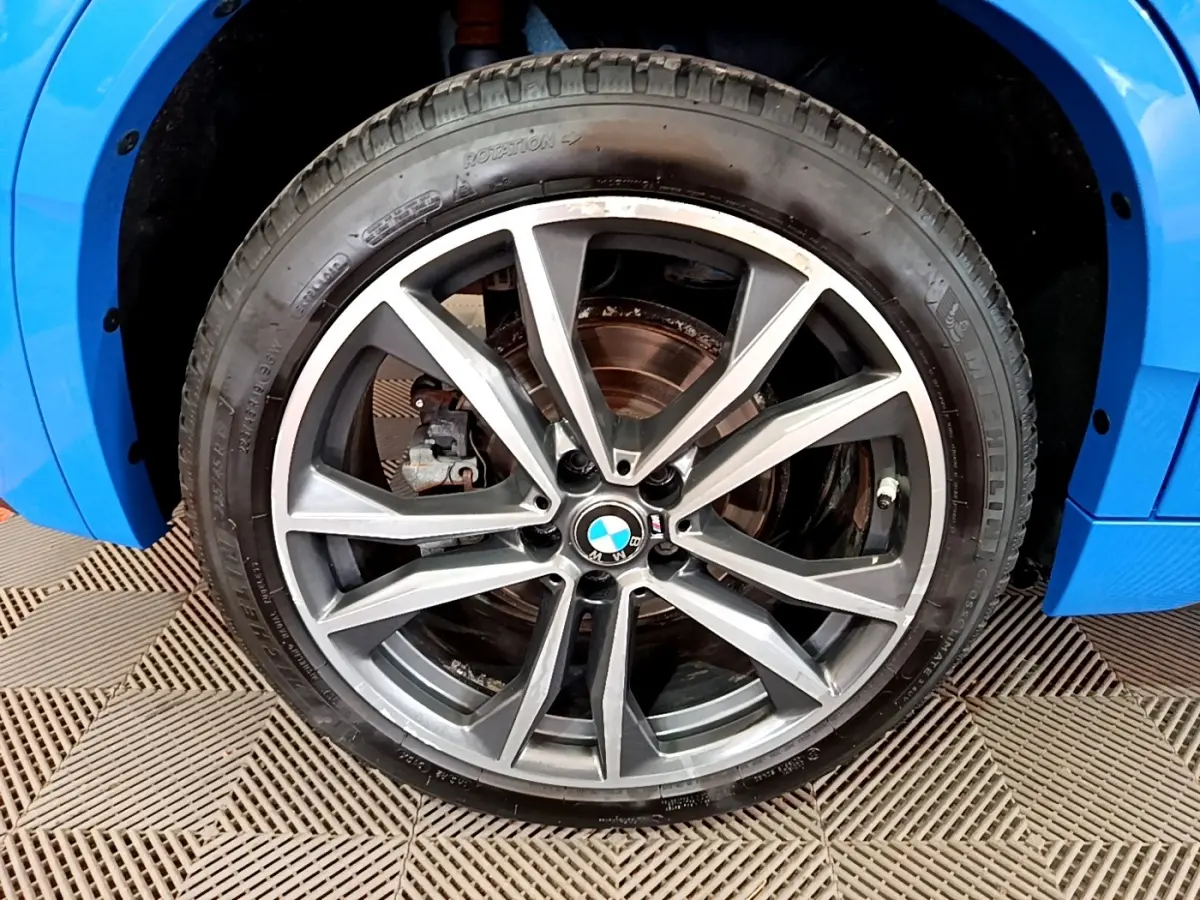Gros plan sur la roue avant gauche d’une BMW X2 bleu 2019 avec jante alliage M Sport à dix branches.