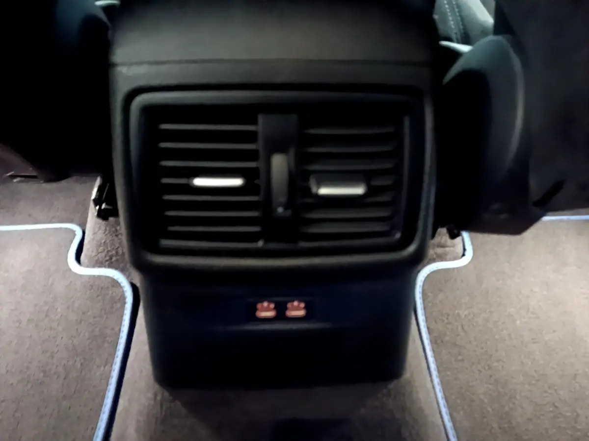 Vue rapprochée des bouches d’aération arrière noires et des ports USB sur la console centrale d’un BMW X2 bleu.