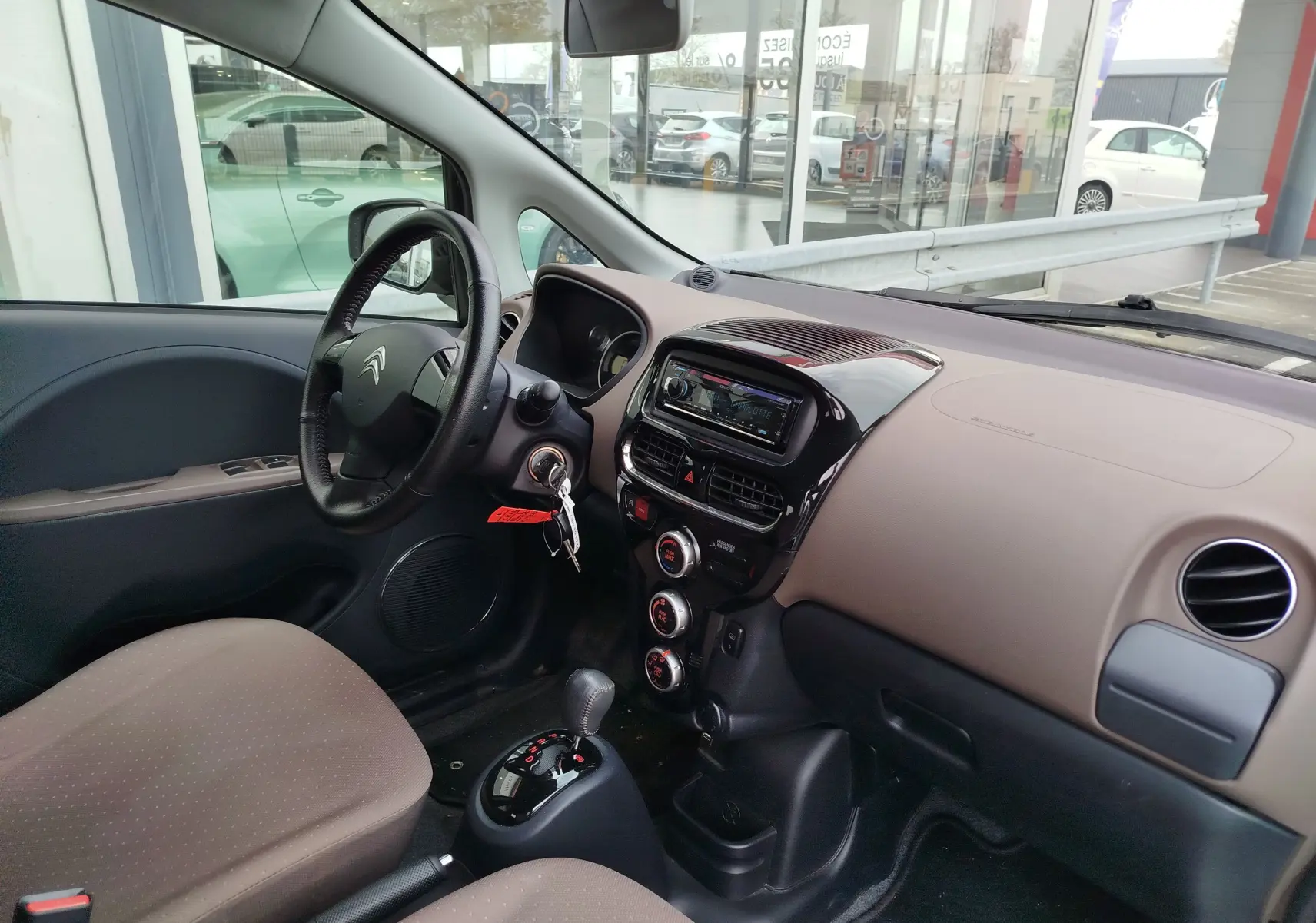 Vue intérieure côté conducteur du Citroën C-ZERO blanc Antarctique 2020, tableau de bord beige et console centrale noire brillante.