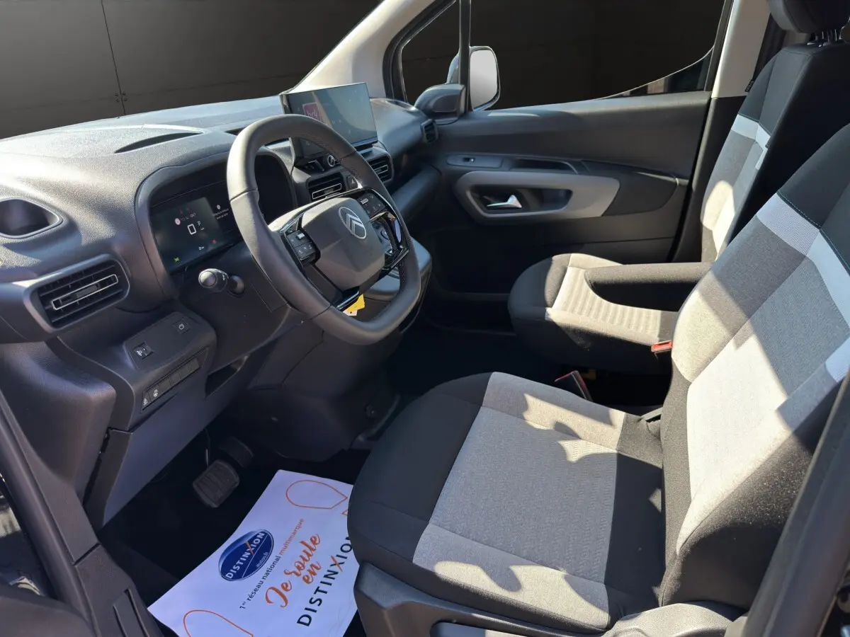 Vue intérieure côté conducteur du Citroën Berlingo noir 2026, avec tableau de bord moderne et sièges tissu bicolore.