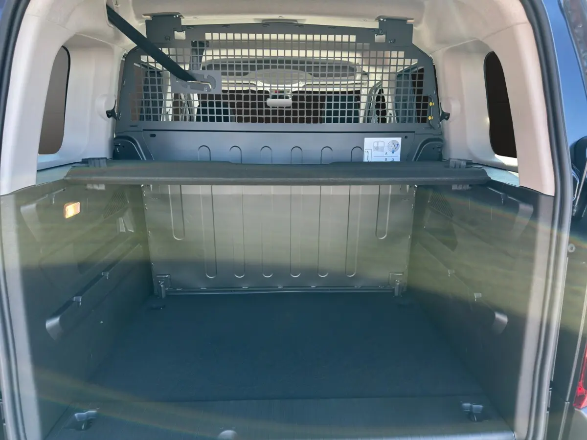 Vue arrière du coffre noir du Citroën Berlingo N1 2026 avec séparation métallique et tablette de rangement.