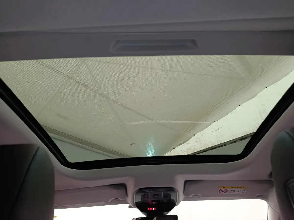 Toit panoramique vu de l'intérieur arrière du DS4 E-TENSE 225 gris clair, mettant en valeur la large surface vitrée.