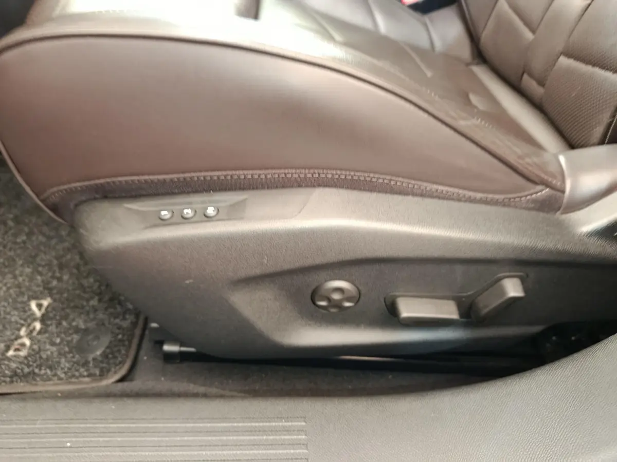 Gros plan sur les commandes de réglage électrique du siège avant droit en cuir marron du DS4 E-TENSE 225 gris clair.