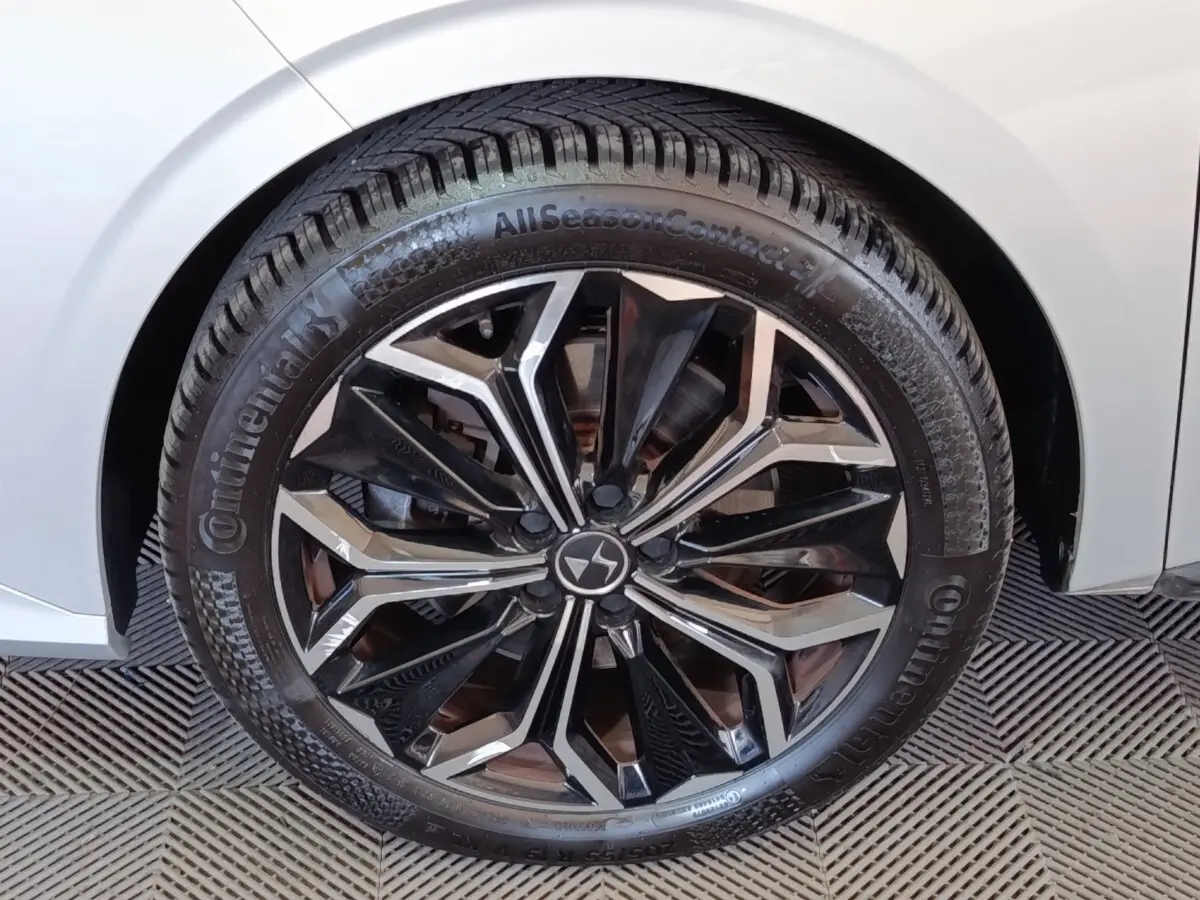 Gros plan sur la roue avant droite d’une DS4 E-TENSE 225 gris clair avec jante alliage noire et argentée.
