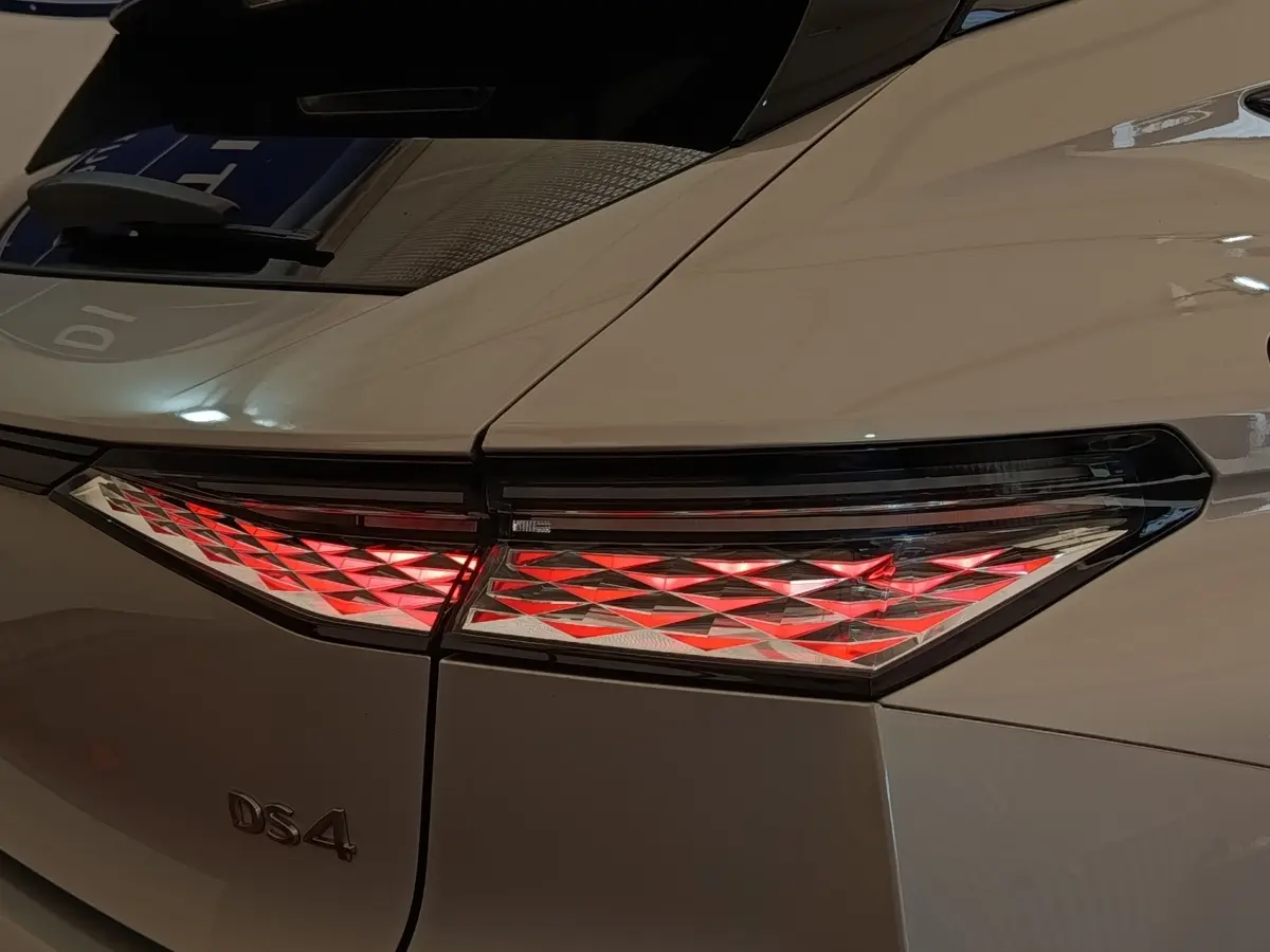 Gros plan sur le feu arrière droit rouge et blanc d’une DS4 E-TENSE 225 gris clair, vue arrière côté droit.