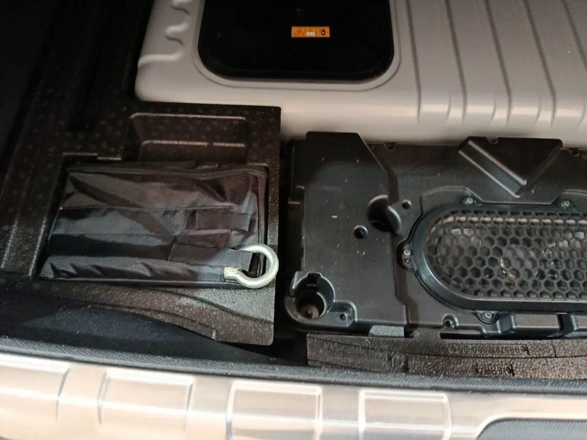 Détail du rangement sous le plancher du coffre du DS4 E-TENSE 225 gris clair, montrant un kit de secours et compartiments.
