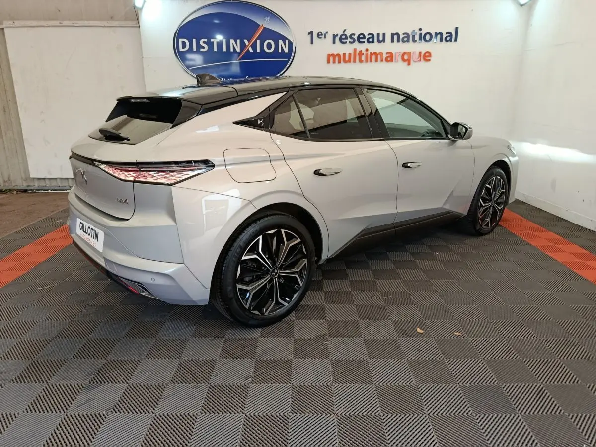 Vue 3/4 arrière droite d'une DS4 E-TENSE 225 gris clair avec feux LED et jantes alliage noires en showroom.