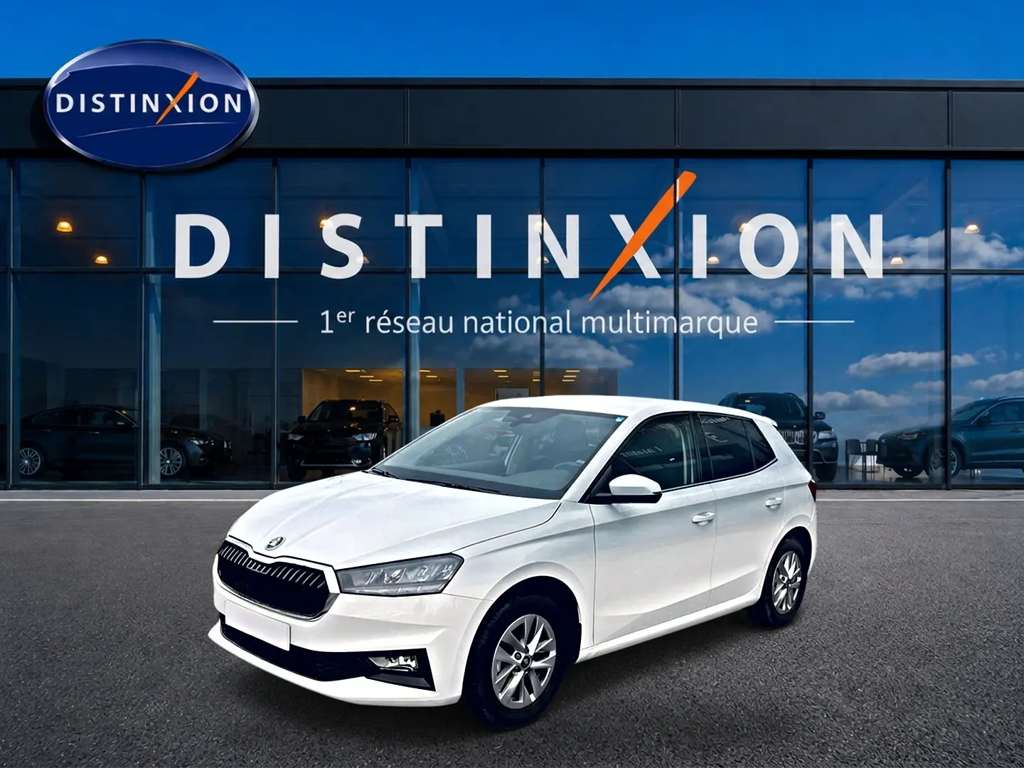 Vue 3/4 avant droite d'une Skoda Fabia blanche garée devant une vitrine avec logo Distinxion.