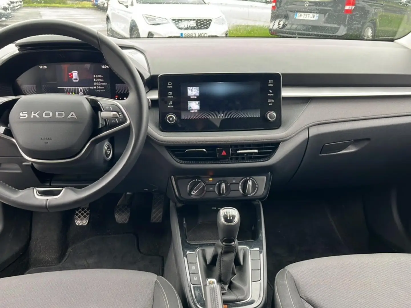 Vue intérieure avant de la Skoda Fabia blanche 2025, volant cuir multifonction et écran tactile central visible.