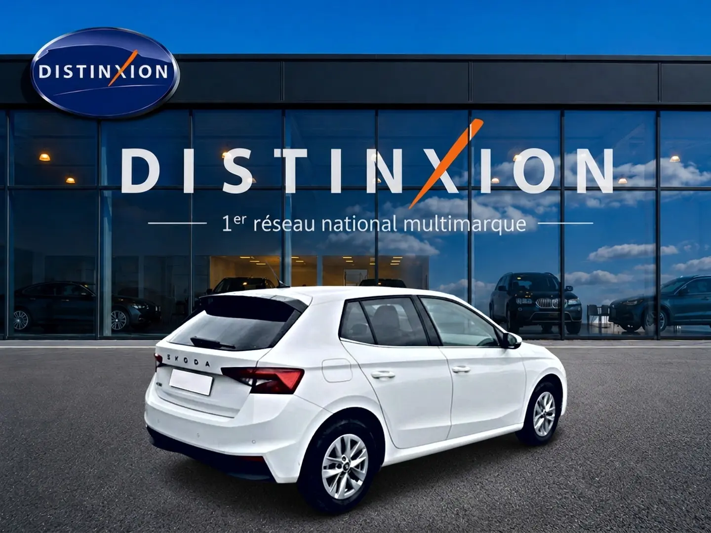 Vue 3/4 arrière droite d'une Skoda Fabia blanche 2025 avec jantes alu et vitres arrière teintées, devant un showroom Distinxion.