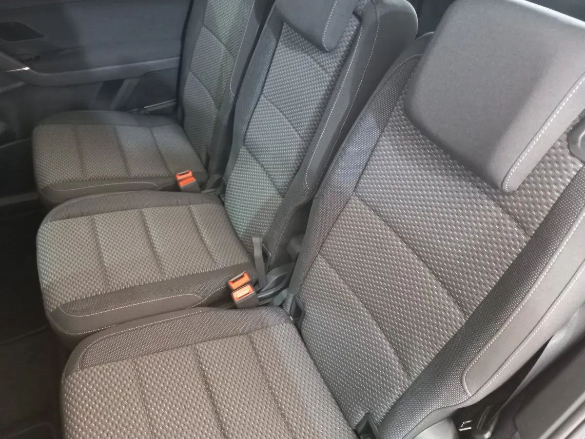 Vue rapprochée des sièges arrière gris texturés du Volkswagen Touran 2024, version 7 places, avec ceintures et boucles visibles.