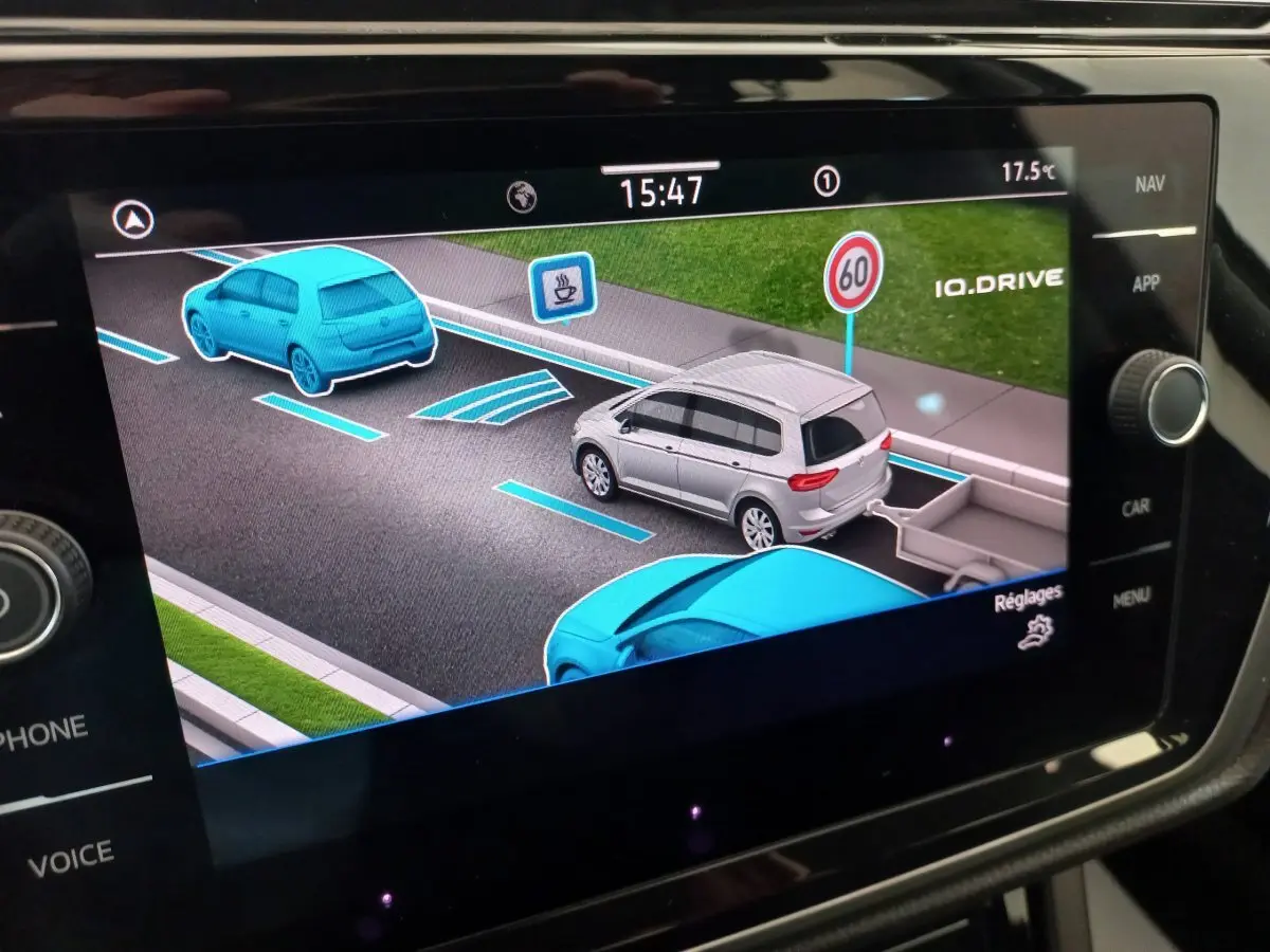 Affichage tactile du système de navigation montrant une Volkswagen Touran grise vue de trois quarts arrière avec remorque virtuelle.
