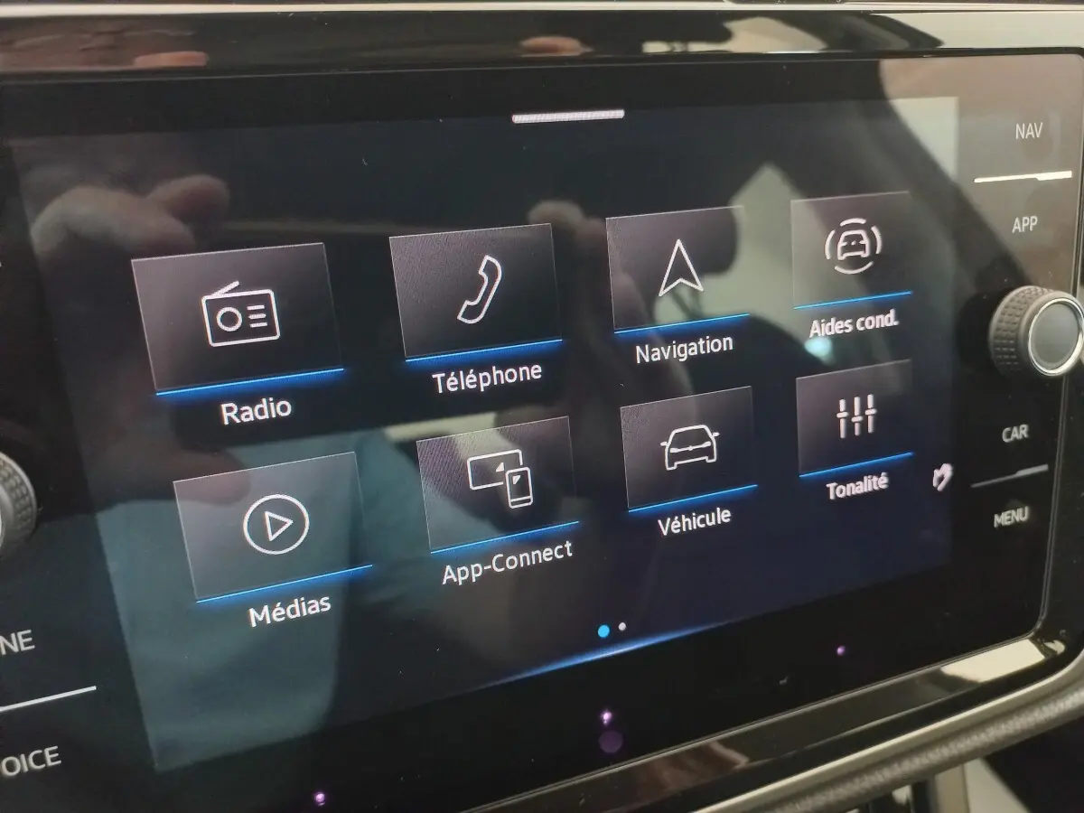 Écran tactile central du Volkswagen Touran 2024 affichant les menus radio, téléphone, navigation et aides à la conduite.