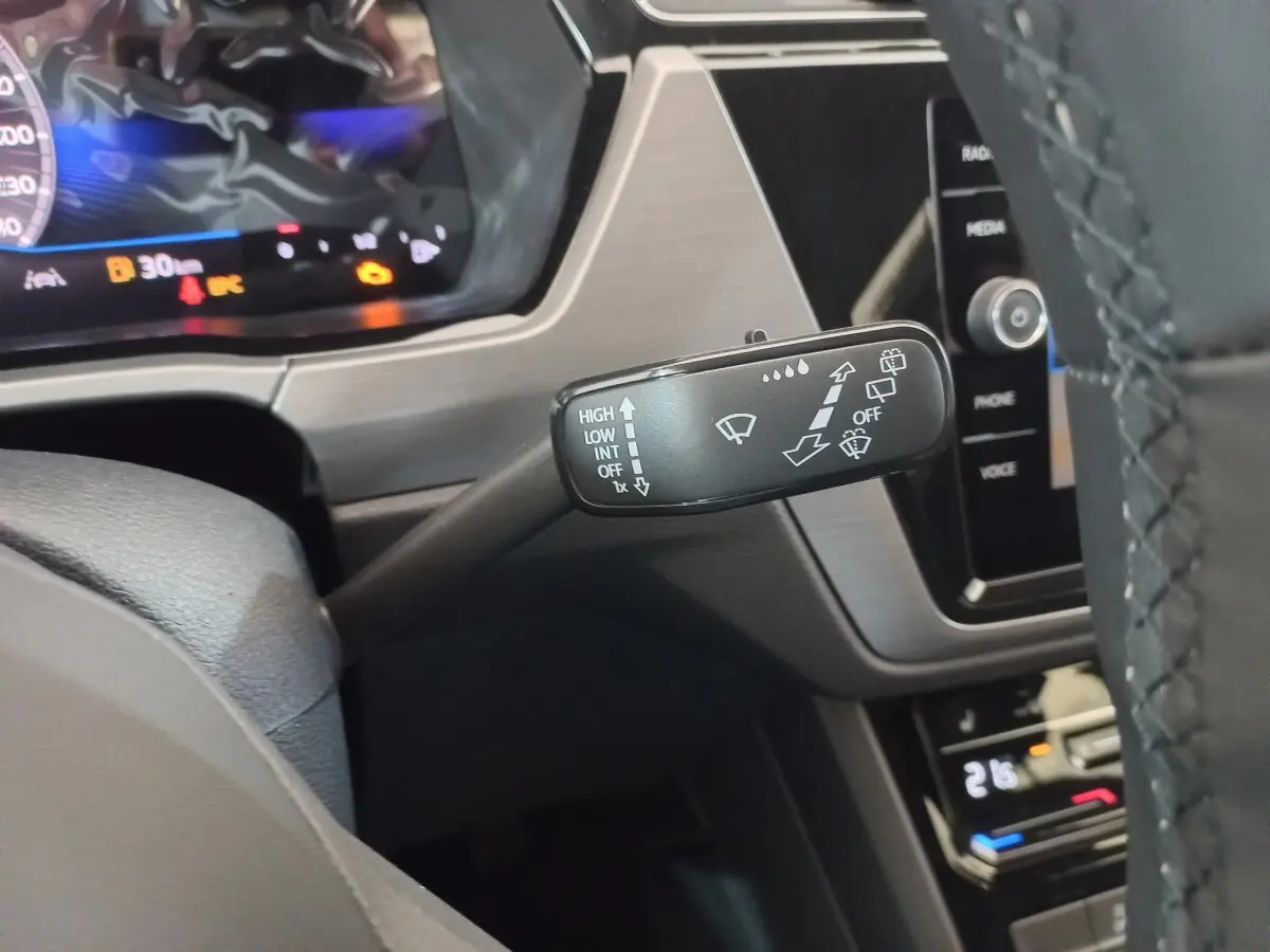 Gros plan sur la commande d’essuie-glace à gauche du volant dans l’habitacle noir du Volkswagen Touran 2024.