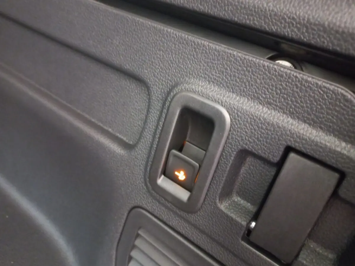 Détail du bouton de rabattement électrique des sièges arrière sur la garniture intérieure noire du Volkswagen Touran 2024.
