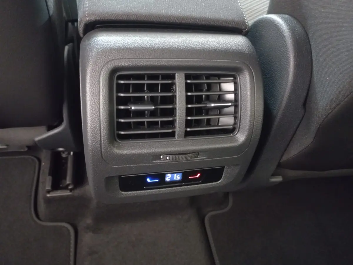 Vue rapprochée des bouches d'aération arrière et commande de climatisation digitale dans un Volkswagen Touran noir 2024.