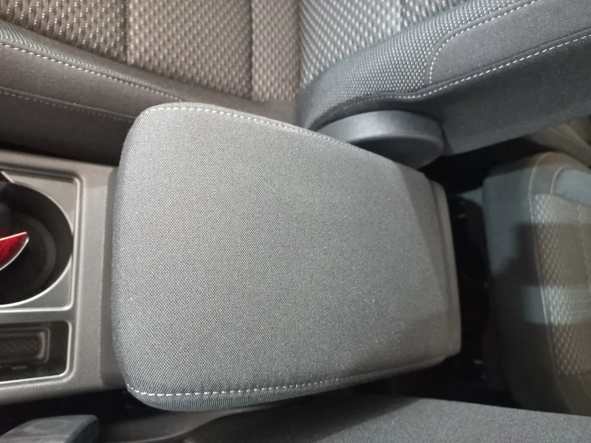 Détail de l'accoudoir central en tissu gris dans l'habitacle du Volkswagen Touran 2024, vue de dessus.