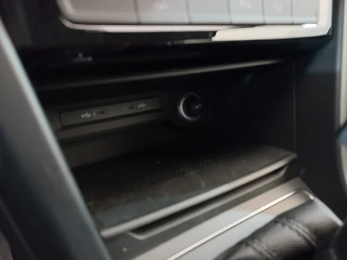 Gros plan sur la console centrale noire du Volkswagen Touran 2024, montrant les ports USB et prise 12V.