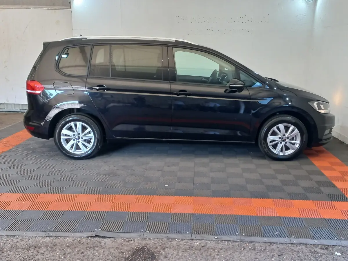 Vue de profil côté gauche d'un Volkswagen Touran noir 2024, avec jantes alliage et vitres teintées.