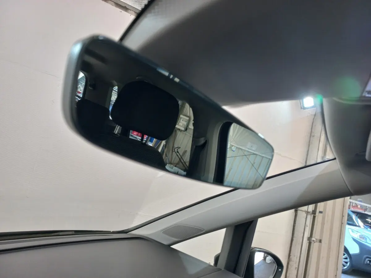Vue intérieure du rétroviseur central du Volkswagen Touran noir 2024, montrant l'arrière des sièges et une partie du toit ouvrant.