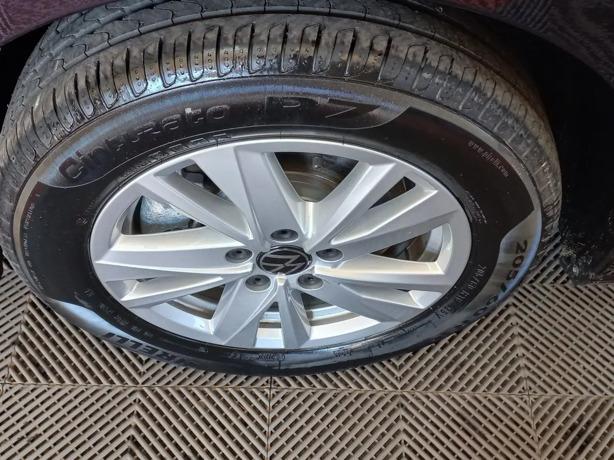 Gros plan sur la roue avant droite du Volkswagen Touran noir 2024 avec jante alliage argentée et pneu Pirelli.
