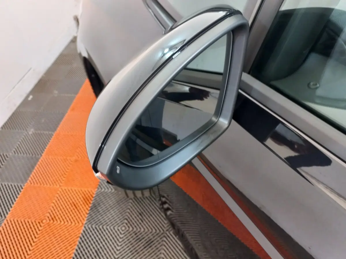 Rétroviseur côté gauche gris métallisé du Volkswagen Touran noir, vue rapprochée avec reflet sur la portière.
