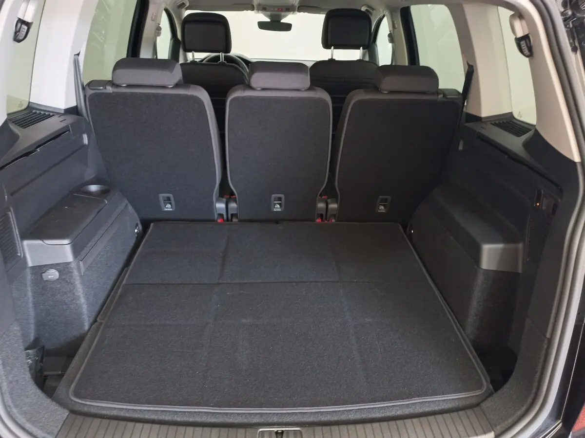 Vue arrière du coffre noir du Volkswagen Touran 2024 avec sièges arrière en position verticale et plancher plat.