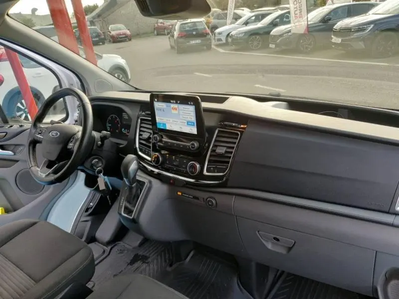 Intérieur du Ford Transit Custom 2020, tableau de bord moderne avec écran tactile central et volant à gauche.