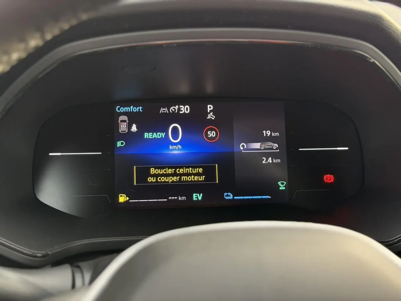 Tableau de bord numérique du Renault Captur hybride 2025 affichant la vitesse, alertes et mode confort, vue frontale rapprochée.