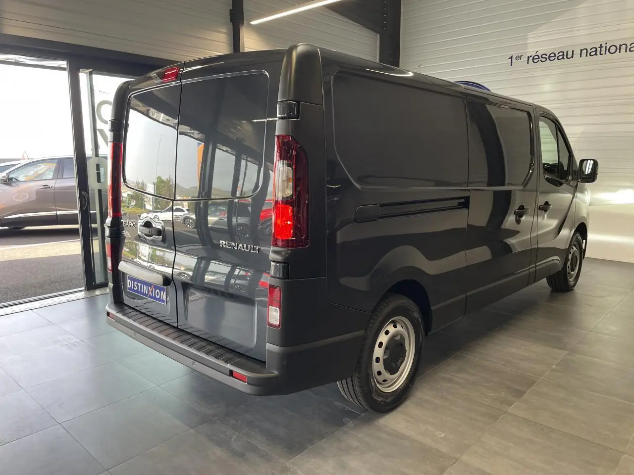 Vue 3/4 arrière droite du Renault Trafic Fourgon gris Comète, avec portes arrière fermées et jantes tôlées 16 pouces.