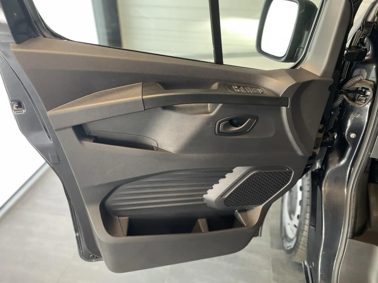 Vue intérieure de la porte avant gauche gris comète du Renault Trafic Fourgon avec commandes de vitres et haut-parleur intégré.