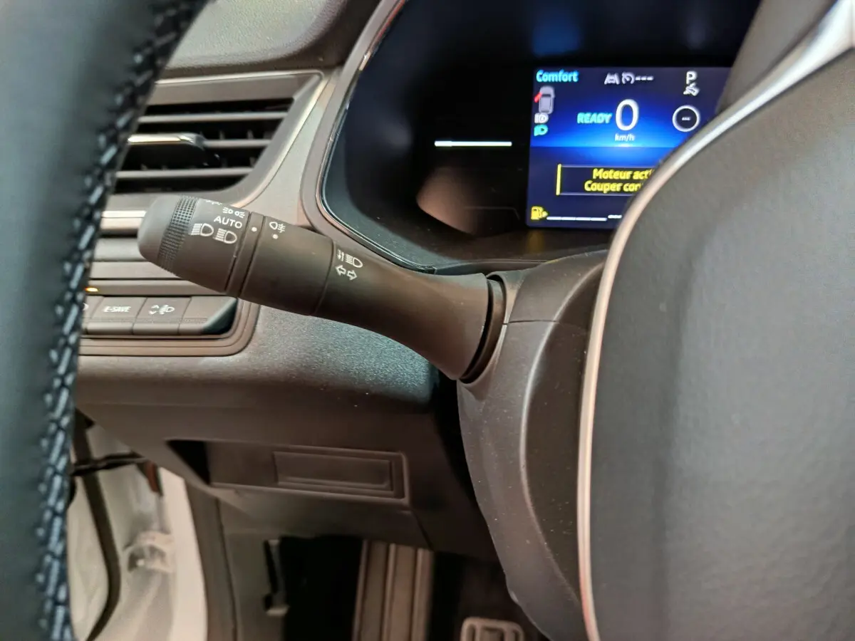Détail du combiné d'instruments numérique et commande des phares sur le volant d'un Renault Captur blanc 2025.