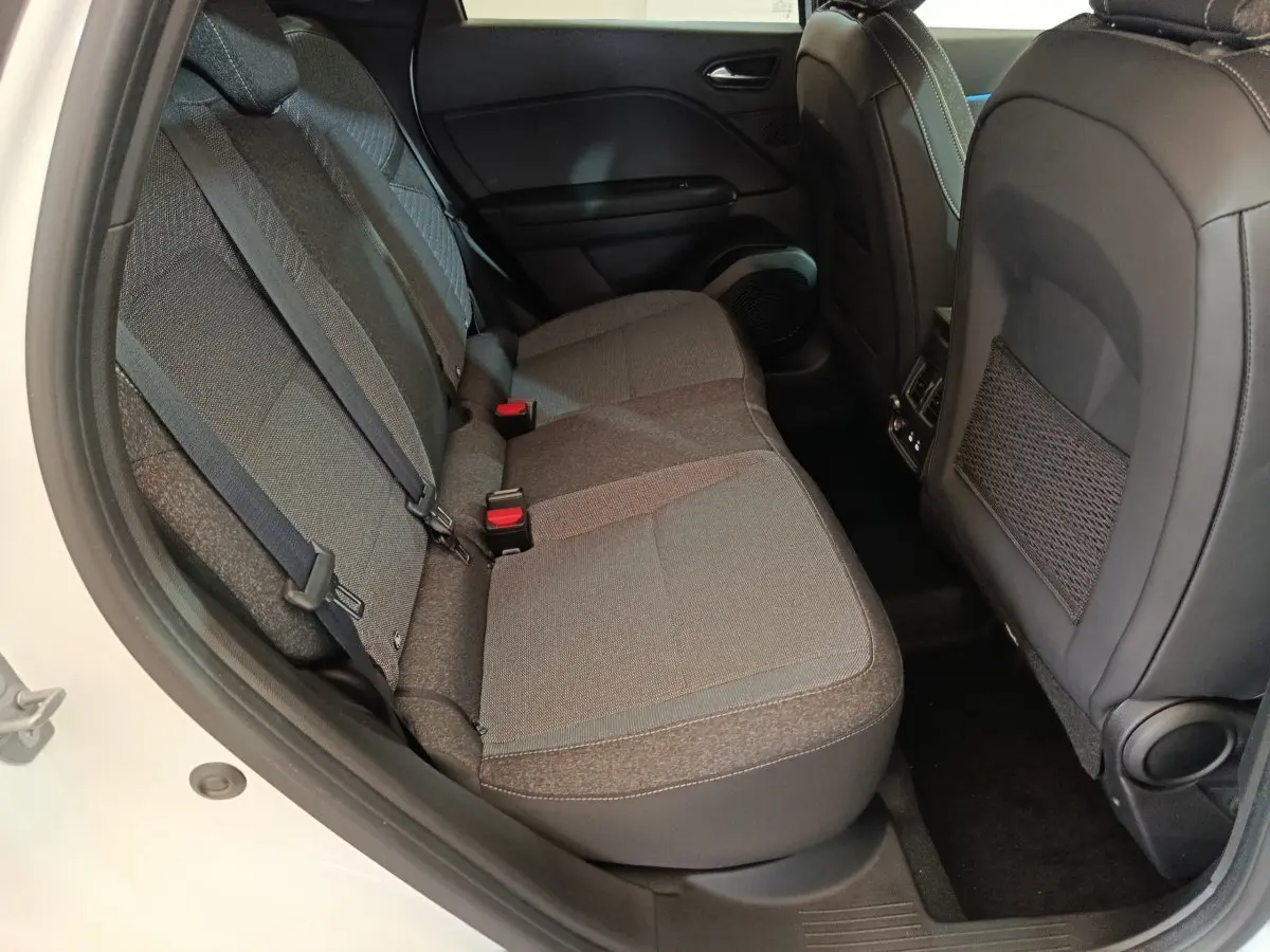 Vue latérale intérieure du siège arrière gris du Renault Captur blanc, avec ceintures de sécurité et dossier avant en cuir noir.