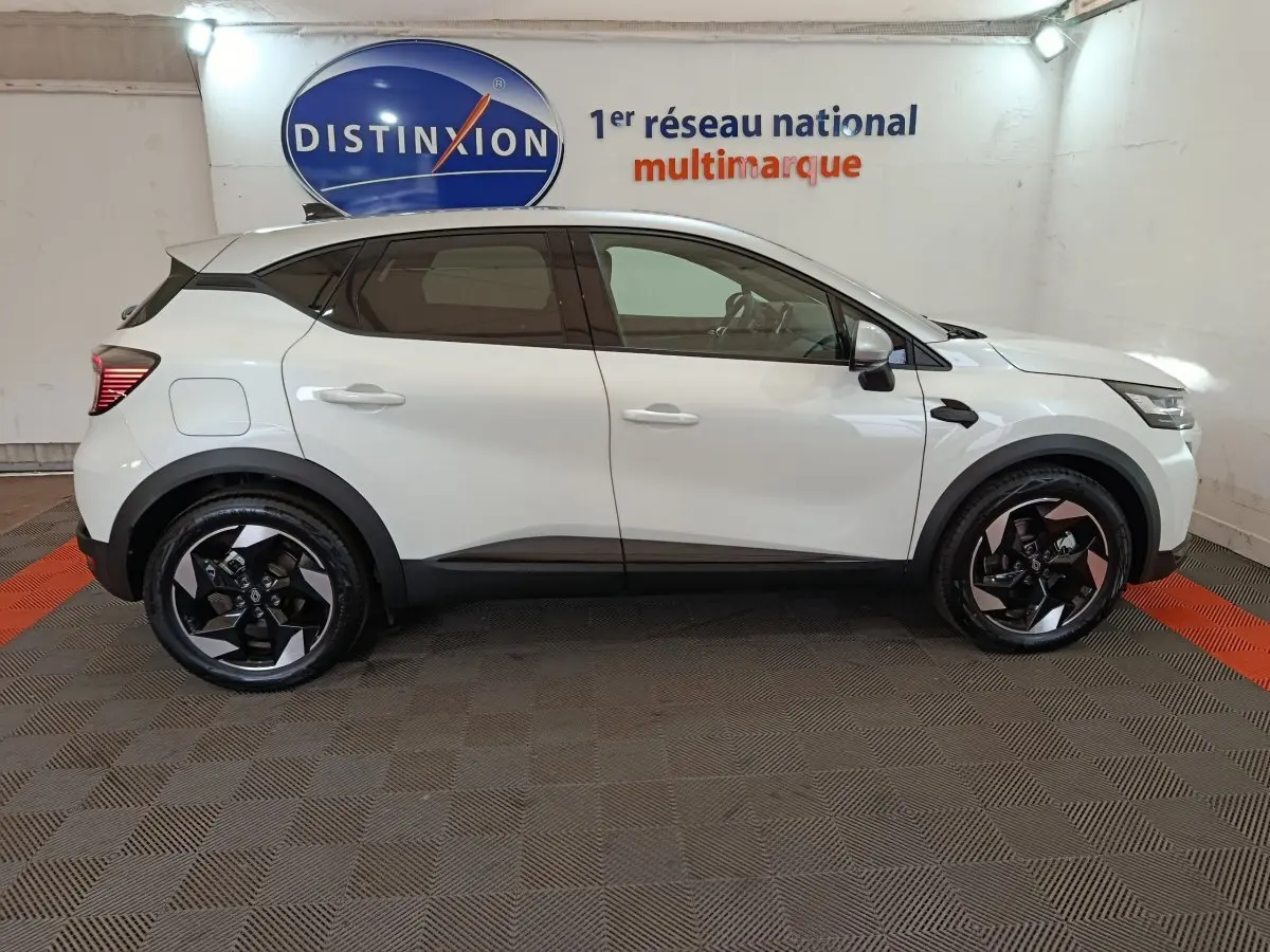 Renault Captur Techno E-Tech blanc vu de profil côté gauche, avec jantes noires et toit noir contrastant.