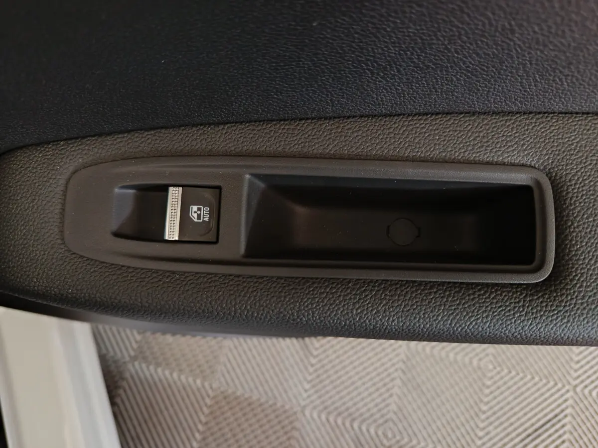 Gros plan sur le bouton de commande de la vitre électrique côté gauche d’un Renault Captur blanc 2025.