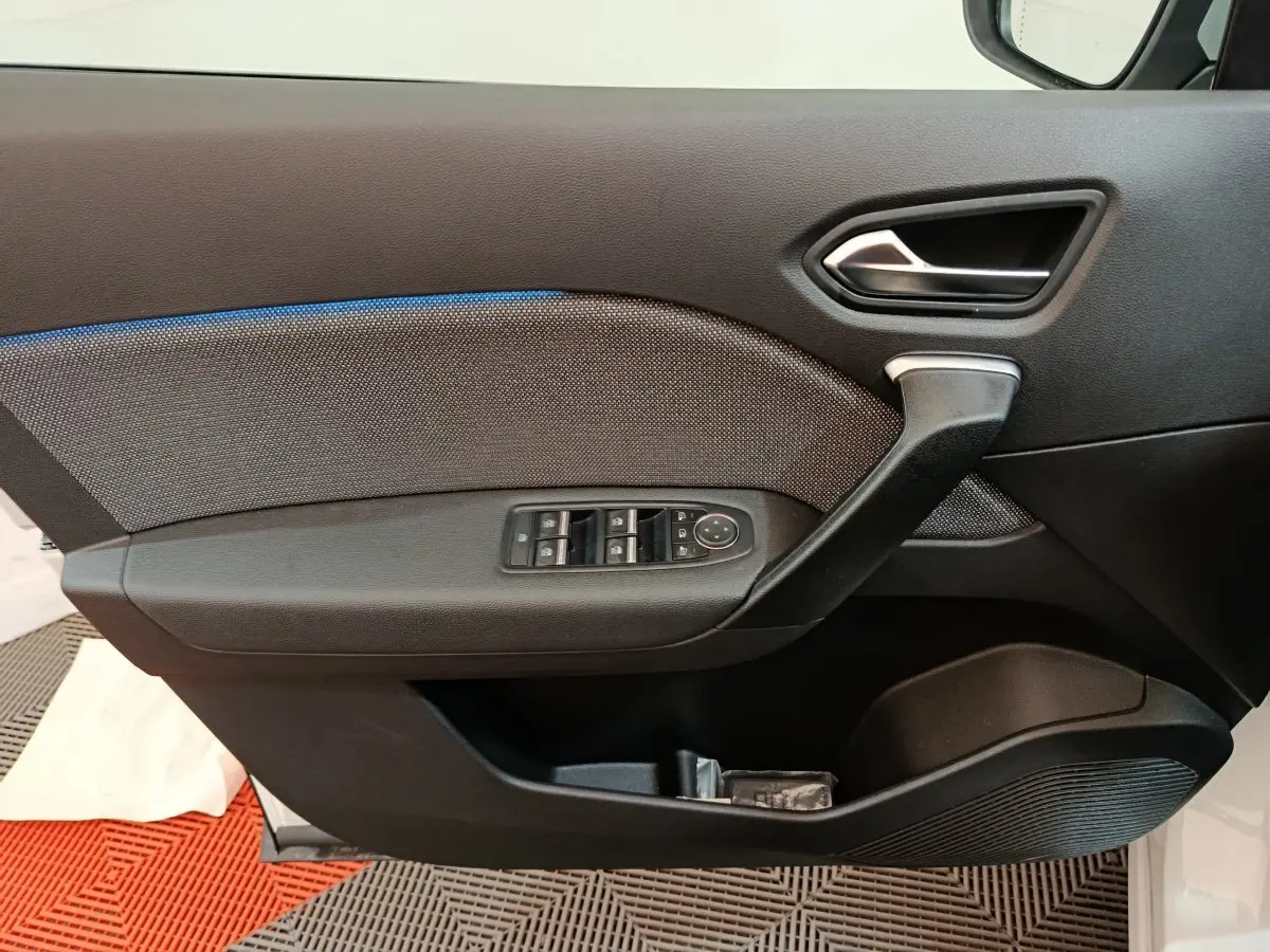 Gros plan sur la porte avant gauche du Renault Captur blanc 2025, avec commandes de vitres et poignée intégrée.