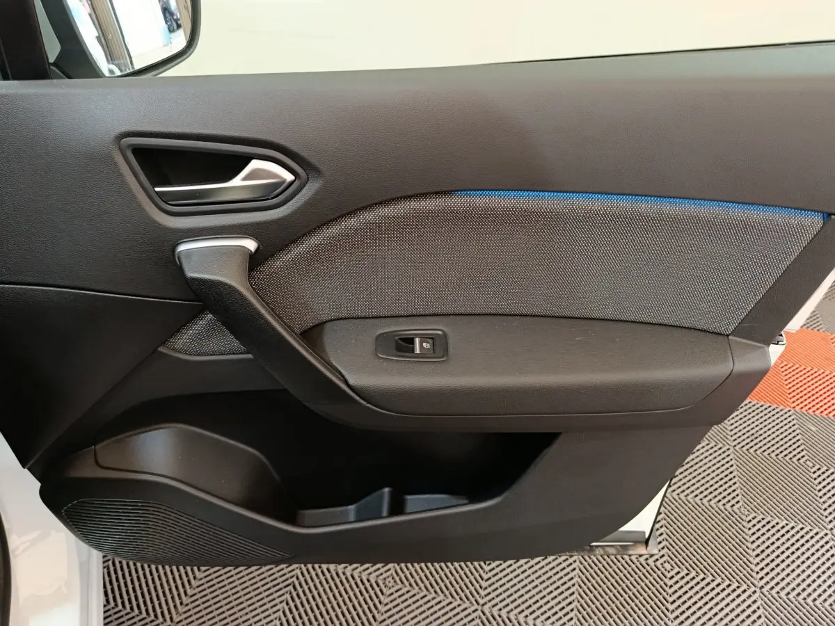 Vue intérieure du panneau de porte côté gauche du Renault Captur blanc, avec bouton de commande de vitre et insert texturé.