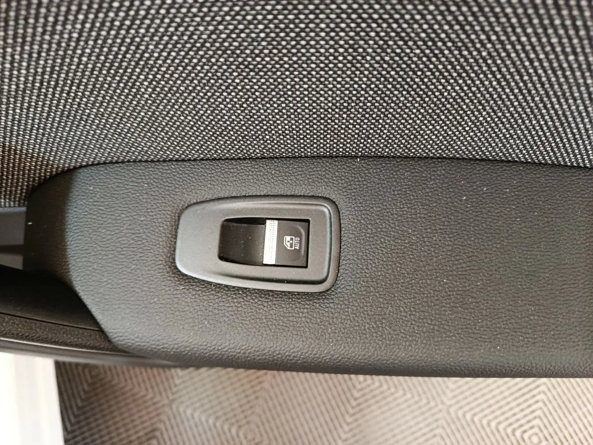 Gros plan sur l'interrupteur de lève-vitre électrique noir sur la porte intérieure d'un Renault Captur blanc.