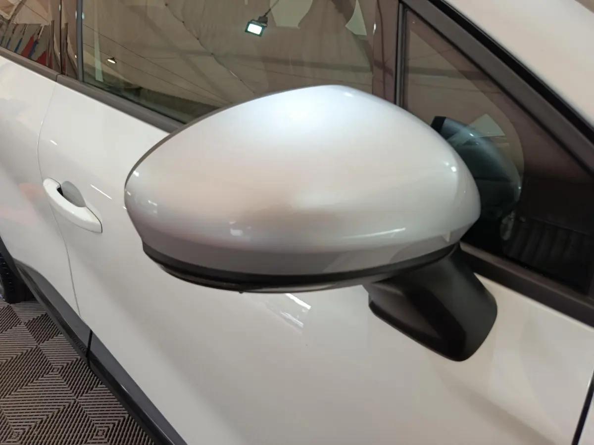 Rétroviseur côté gauche blanc du Renault Captur 2025 techno E-Tech full hybrid, avec porte et vitre partiellement visibles.