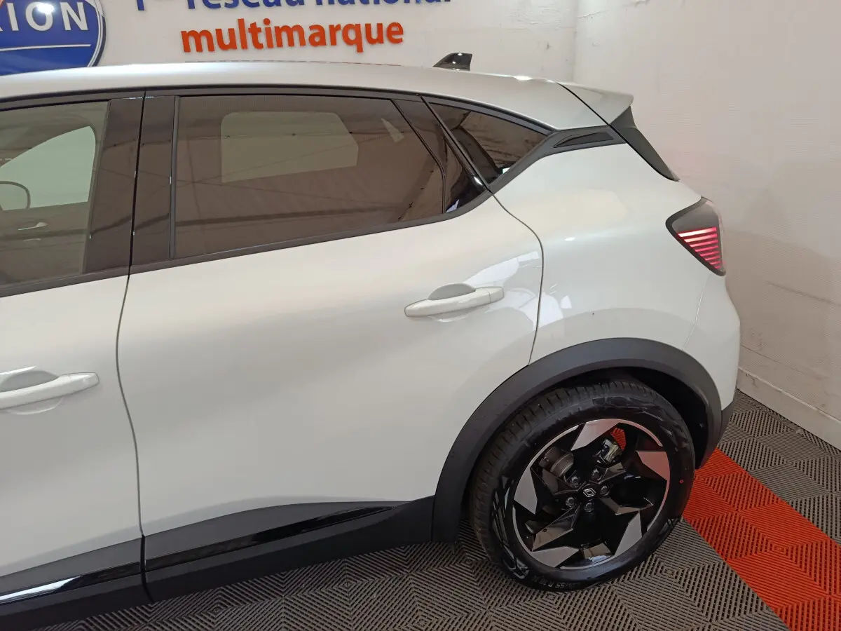 Vue côté droit arrière du Renault Captur blanc 2025, mettant en valeur la porte arrière et la roue au design moderne.