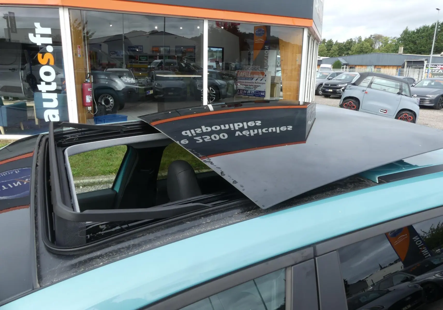 Toit ouvrant électrique ouvert sur le dessus d'une Jeep Avenger bleu métallisé, vue partielle côté gauche.