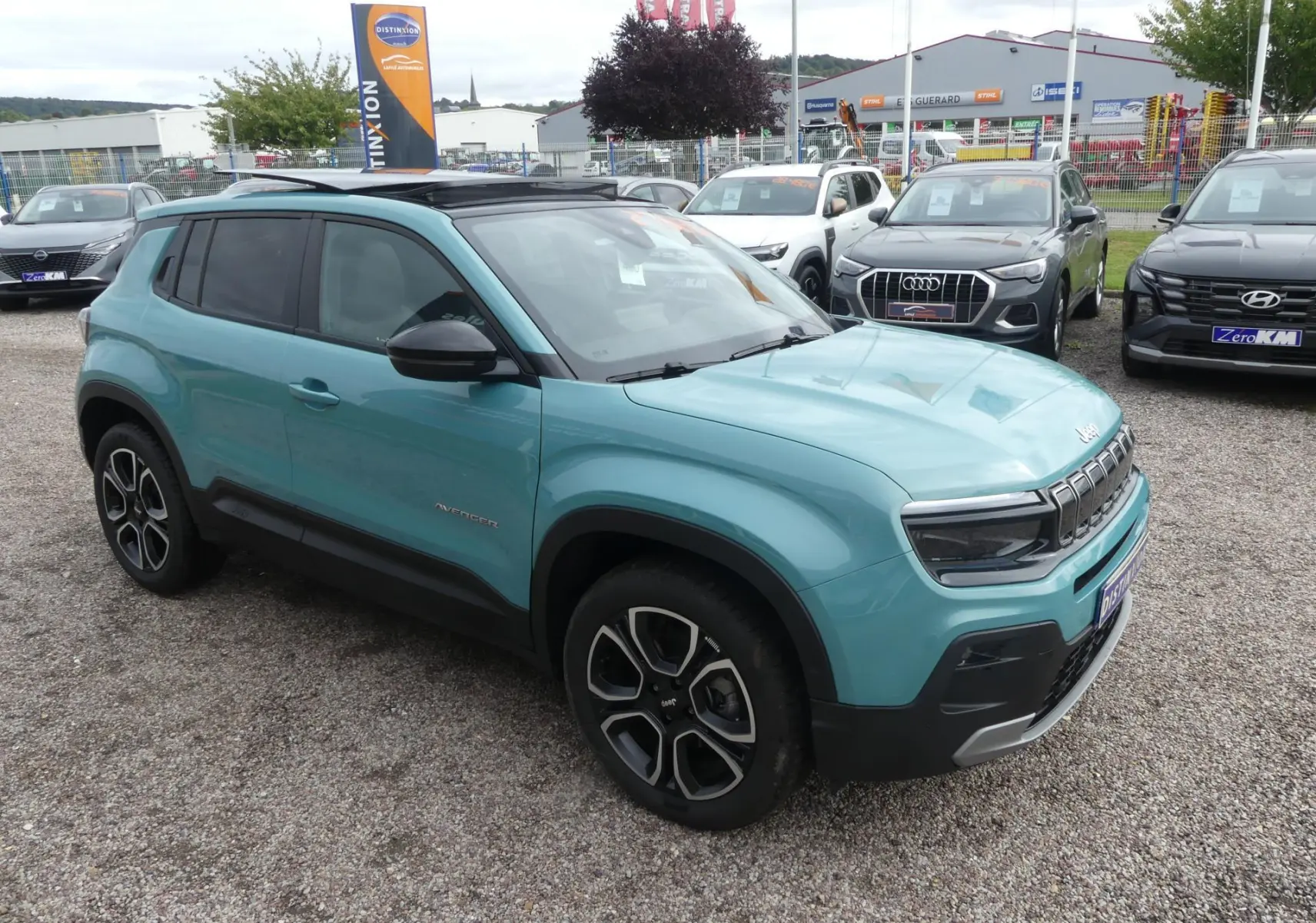 Jeep Avenger bleu métallisé vue 3/4 avant droit avec toit noir et jantes alliage distinctives.