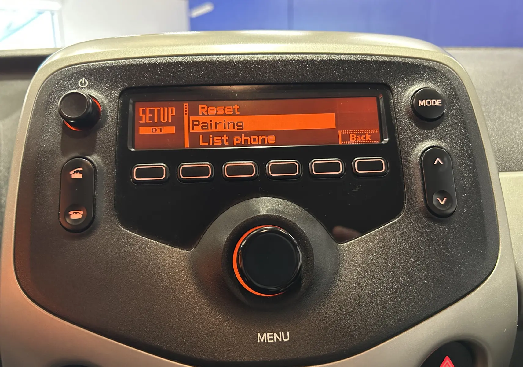 Détail de la console centrale noire de la Peugeot 108 blanche, affichant le menu Bluetooth en orange.