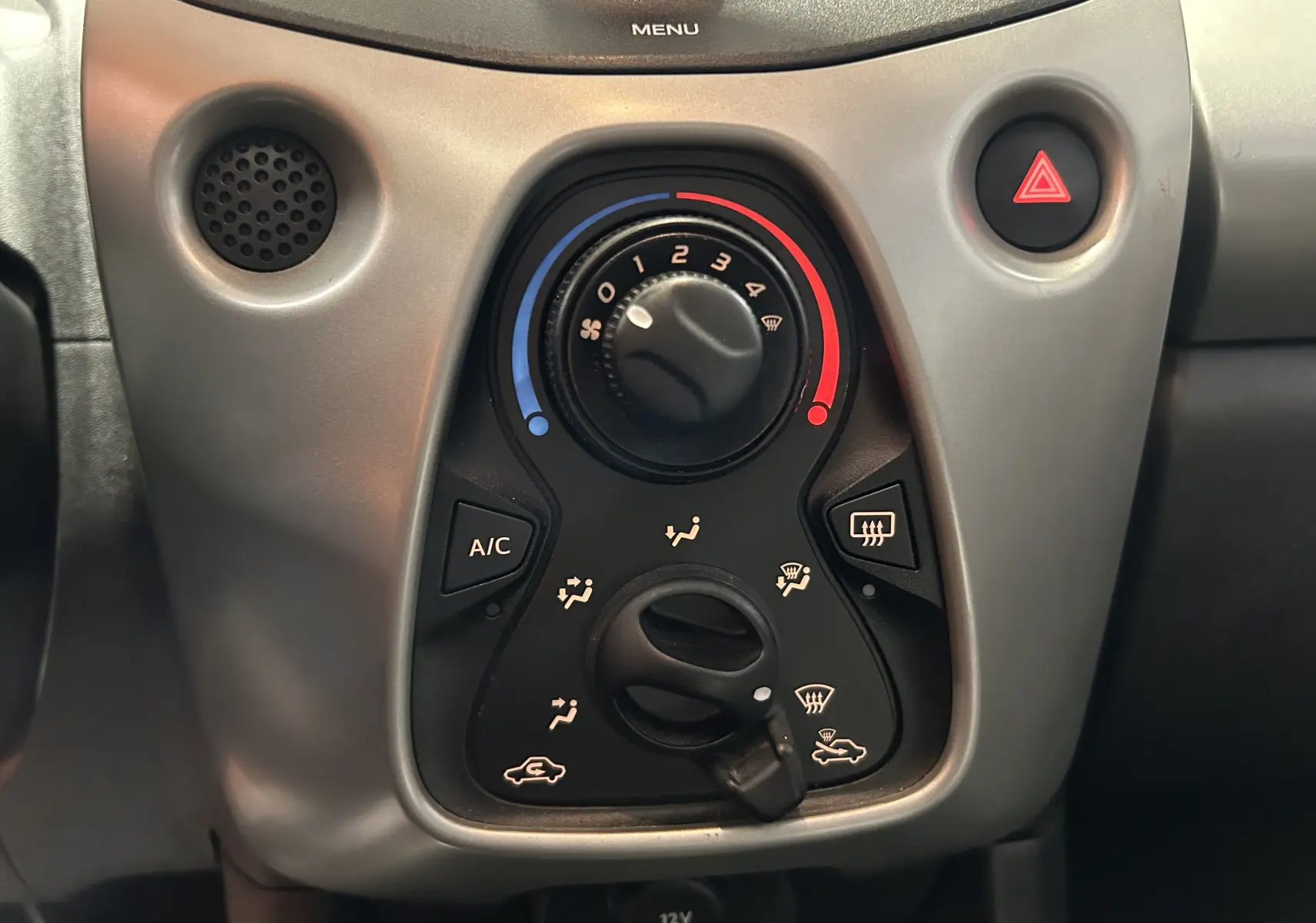 Vue rapprochée des commandes de climatisation et ventilation du tableau de bord d’une Peugeot 108 blanche de 2014.