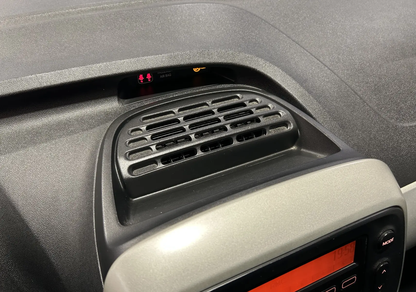 Détail de la console centrale noire et grise avec diffuseur d'air et écran radio de la Peugeot 108 blanche 2014.