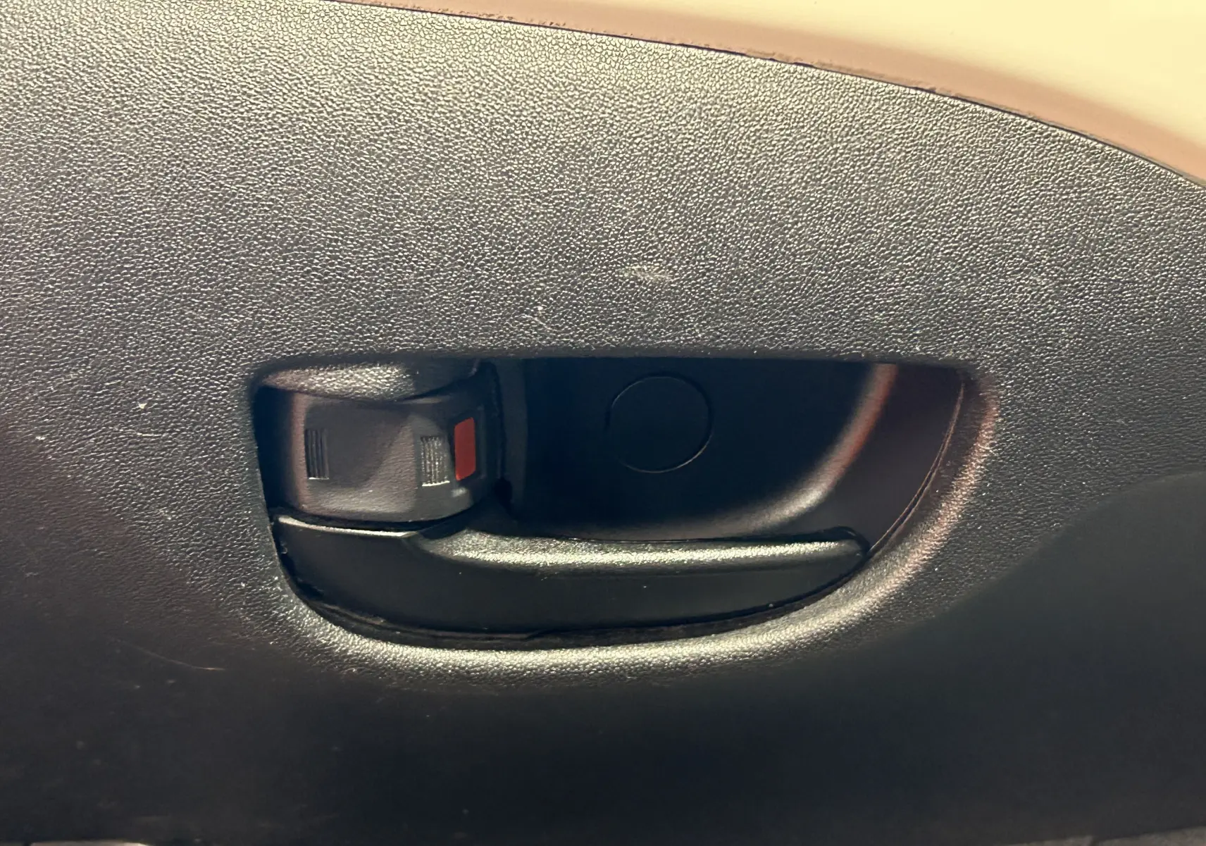 Poignée intérieure de porte noire du Peugeot 108 blanc, vue en gros plan sur la garniture intérieure.