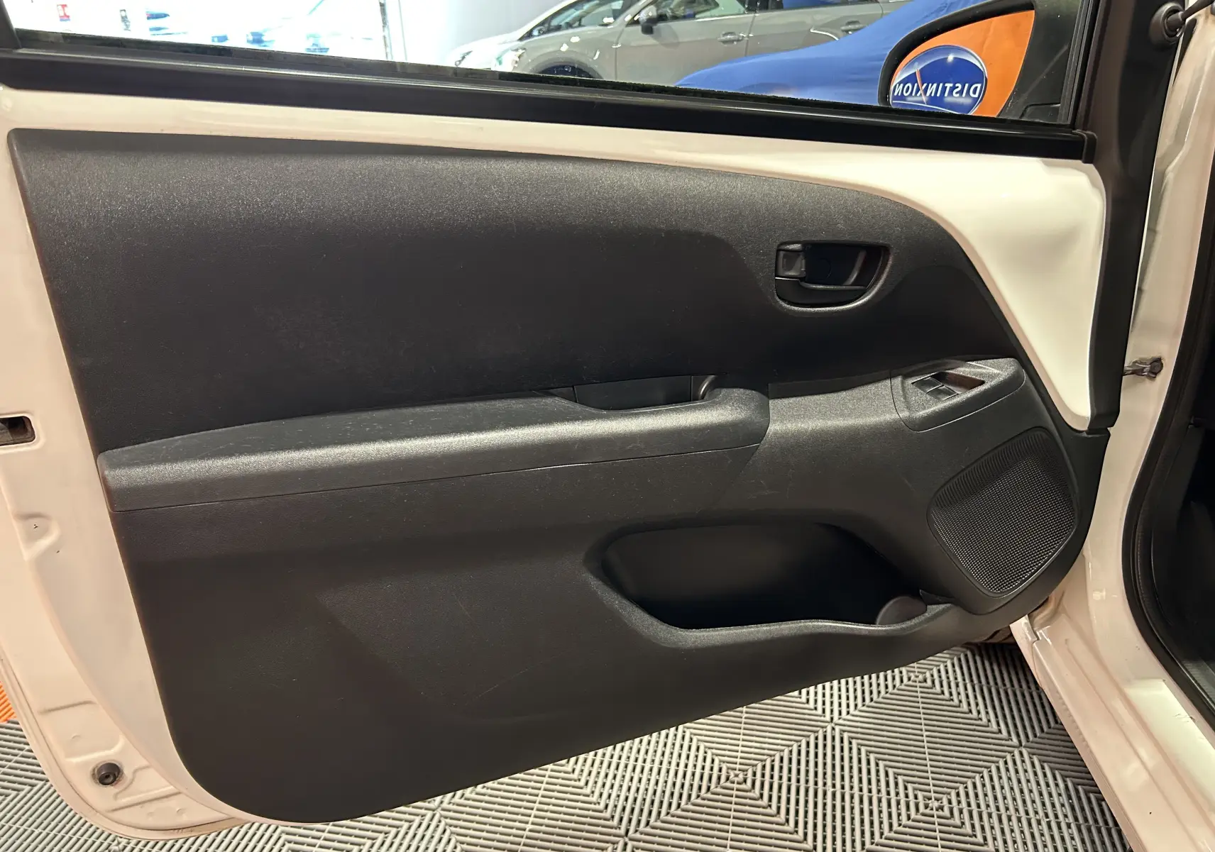 Vue intérieure de la porte avant gauche blanche d'une Peugeot 108 2014, avec panneau noir et commandes de fenêtre.