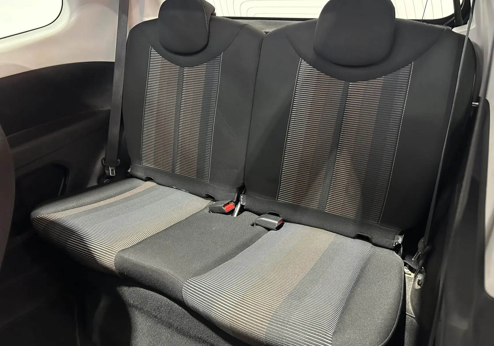 Vue intérieure arrière des sièges arrière en tissu noir et gris du Peugeot 108 blanc, version 2014.