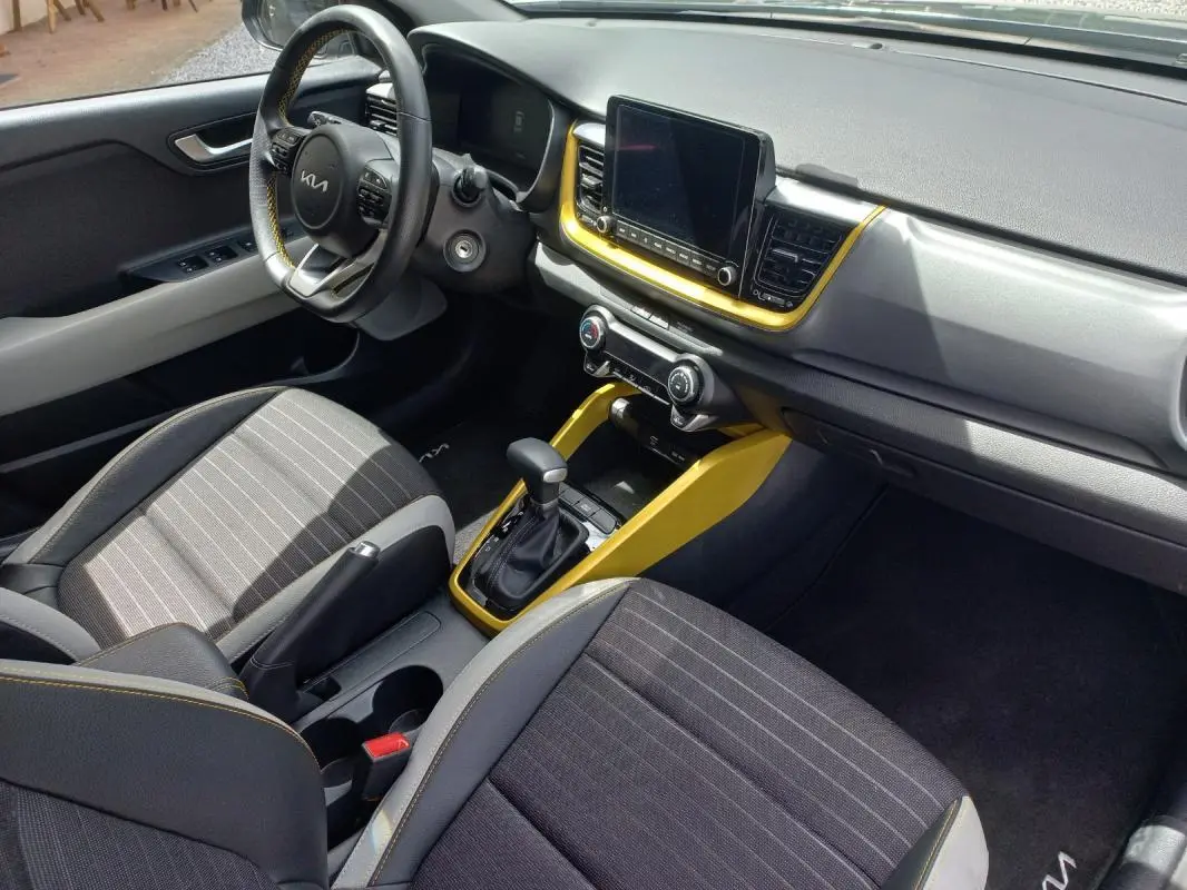 Vue intérieure côté conducteur du Kia Stonic 2025 noir, avec tableau de bord et console centrale soulignés de jaune vif.