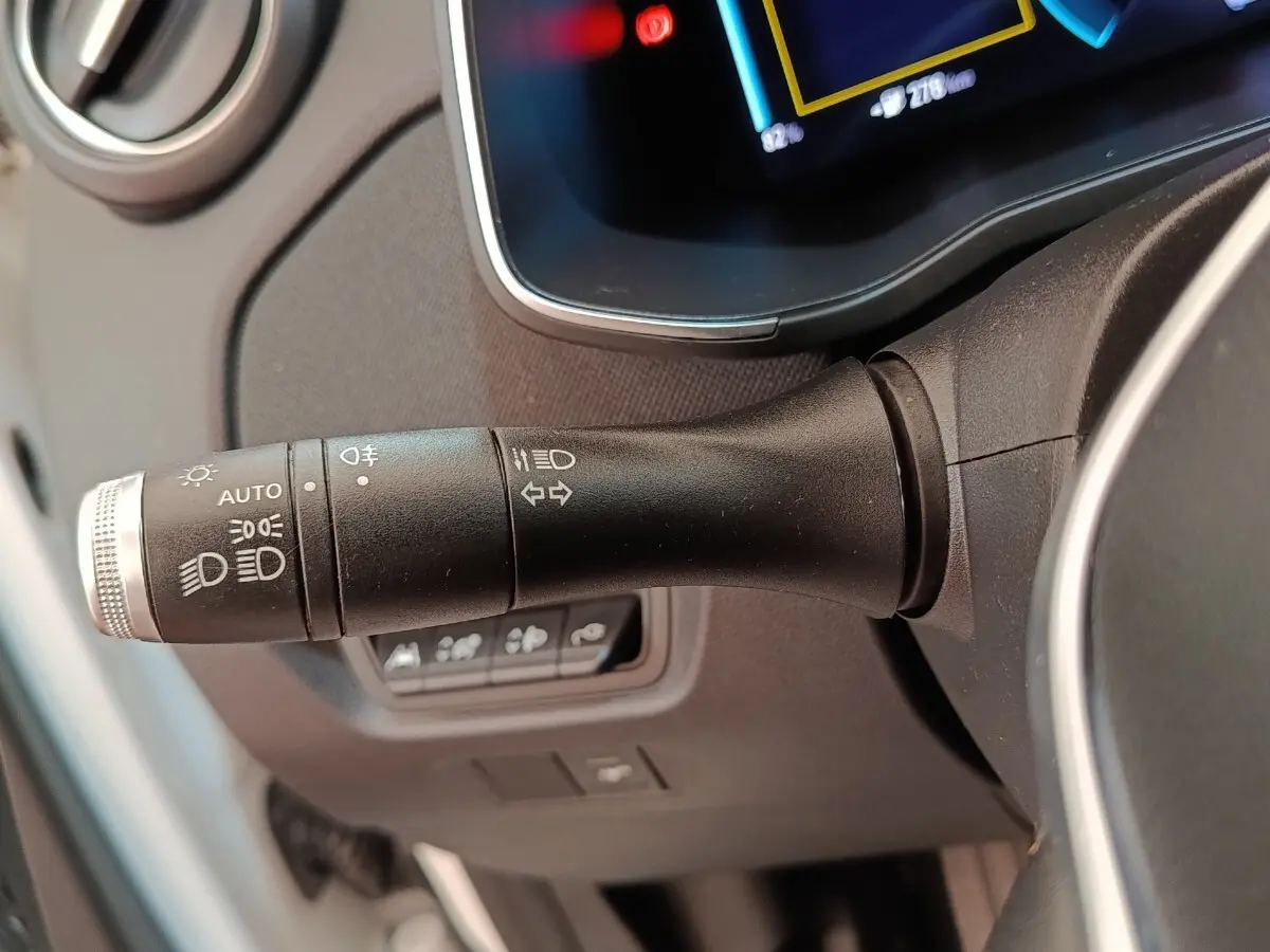 Gros plan sur la commande des phares et clignotants à gauche du volant dans l’habitacle d’une Renault ZOE blanche 2021.